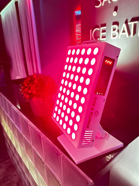 Red light therapy panel emitting bright red light, displayed on a counter with a sign in a spa or wellness setting